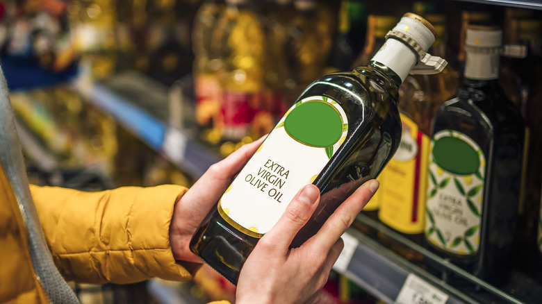 Person holding olive oil bottle