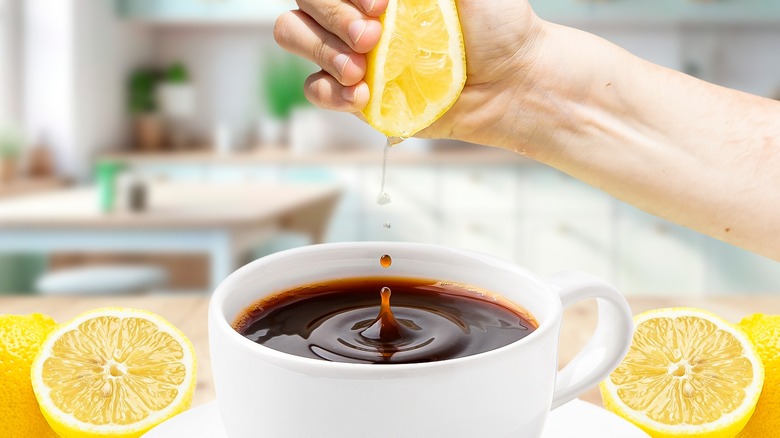 Someone squeezing lemon in coffee