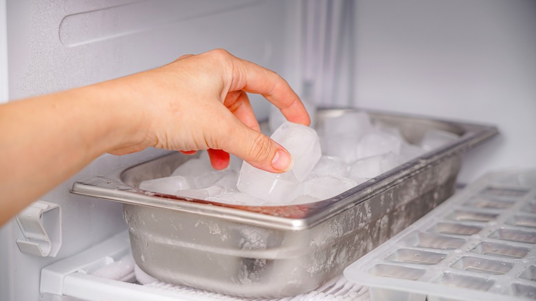 hand reaching for ice cube in freezer 