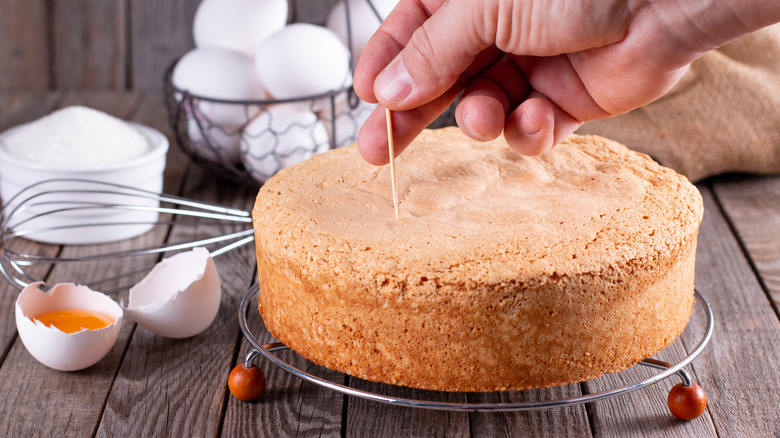 Person testing cake with toothpick