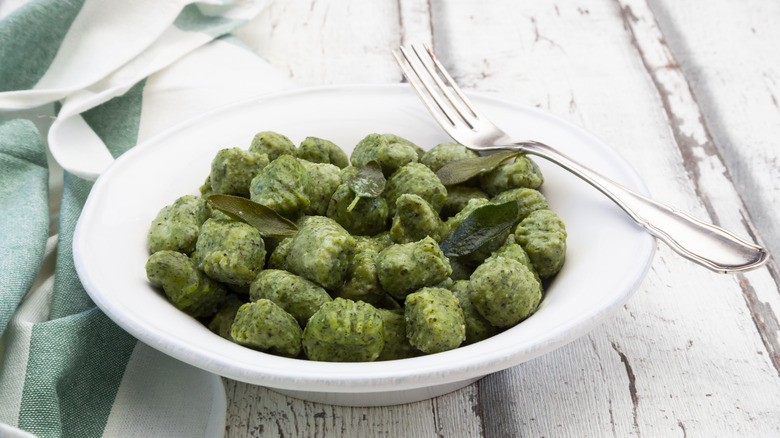 Pesto potato gnocchi in white bowl with fork