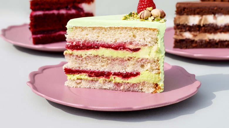 slice of white cake with jam and pistachio frosting