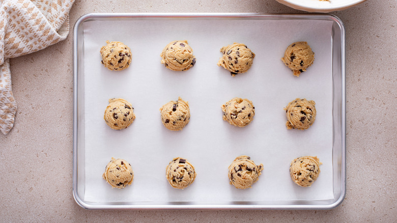 Balls of cookie dough on a parchment-lined baking sheet