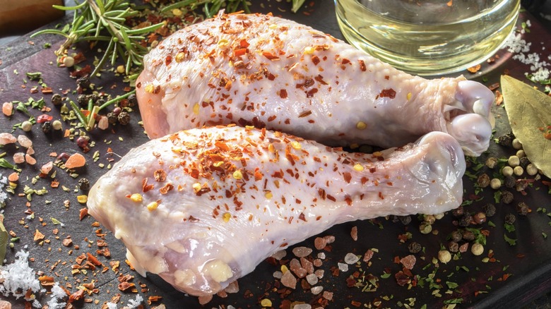 Raw drumsticks seasoned with pink sea salt and crushed red pepper