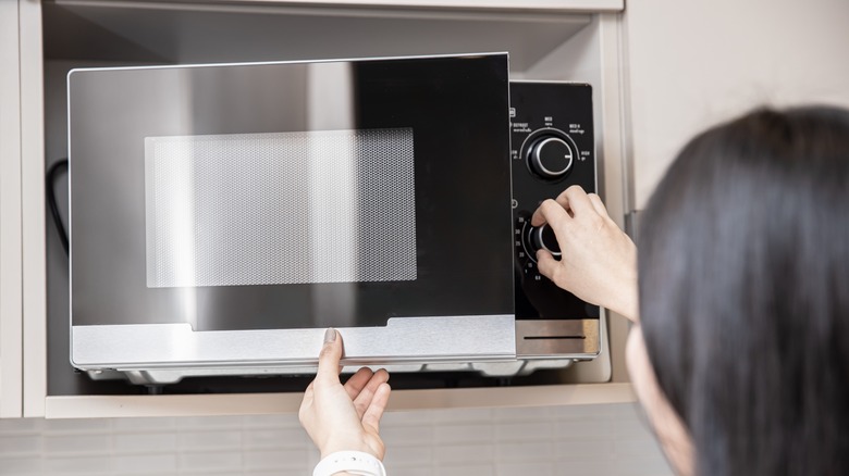 Person adjusting microwave buttons