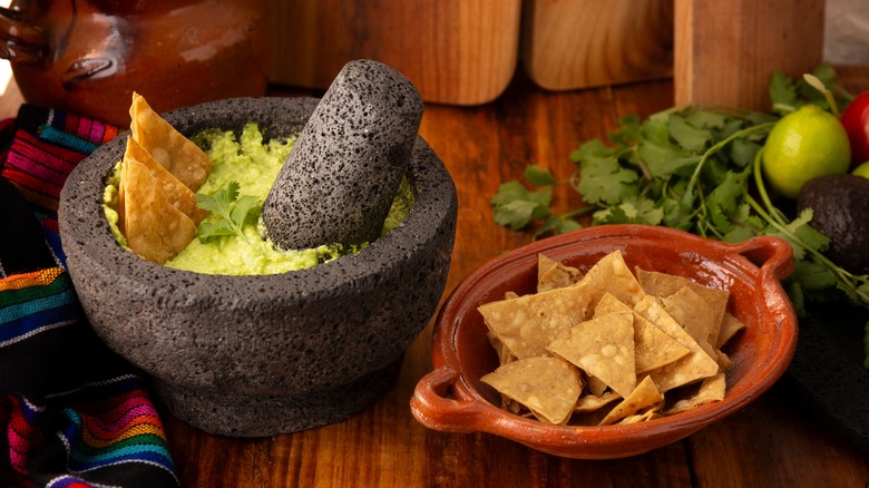 Molcajete with guacamole next to a bowl of tortilla chips