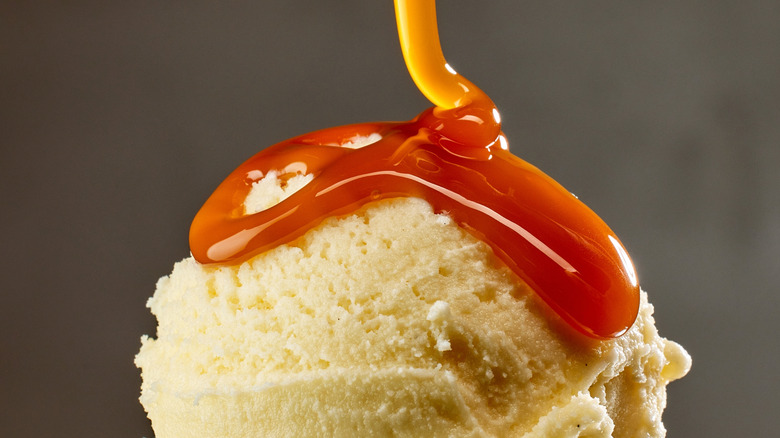 Butterscotch syrup drizzling over scoop of ice cream