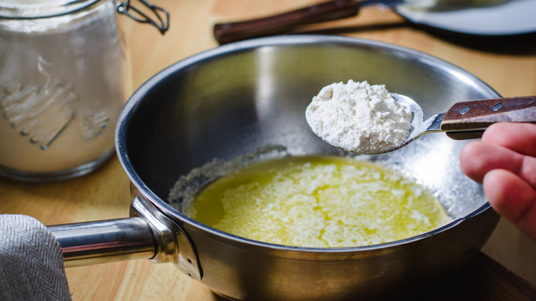 A person making roux with butter and flour in a sauce pot