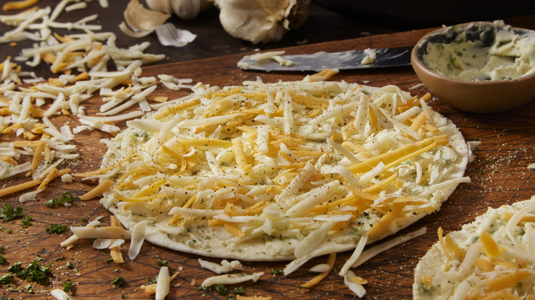 Shredded cheese on flatbread uncooked