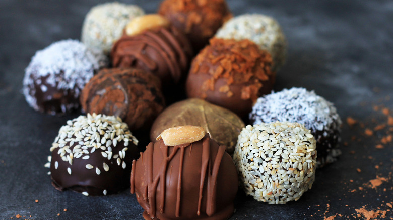 Assorted chocolate truffles on a dark surface