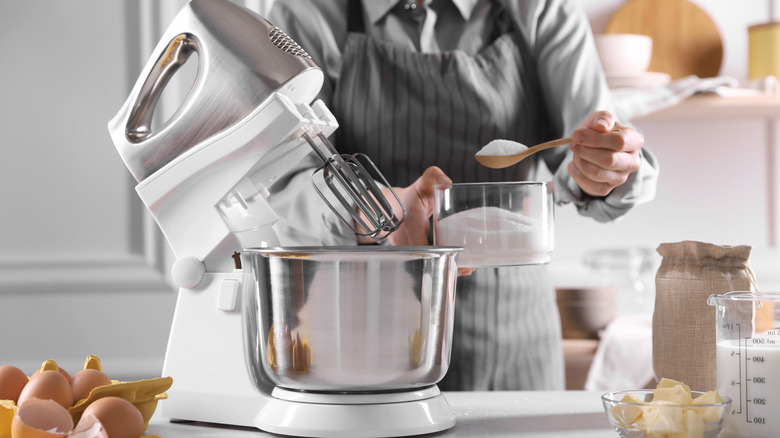 Woman adding ingredients to the bowl of a stand mixer