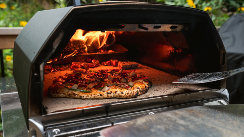 Pizza cooking in an outdoor, portable pizza oven