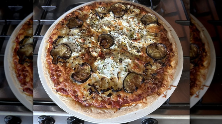 Pizza on pizza stone coming out of the oven