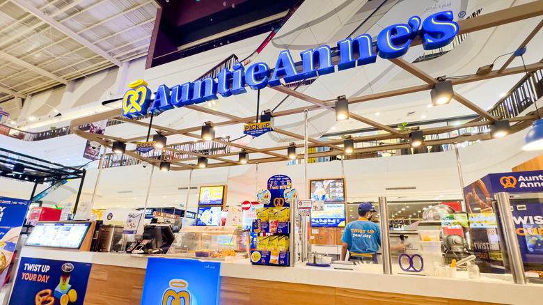 a well-lit Auntie Anne's sign and counter with pretzels and treats