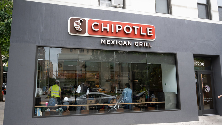 corner storefront of a Chipotle Mexican grill with customers visible through window