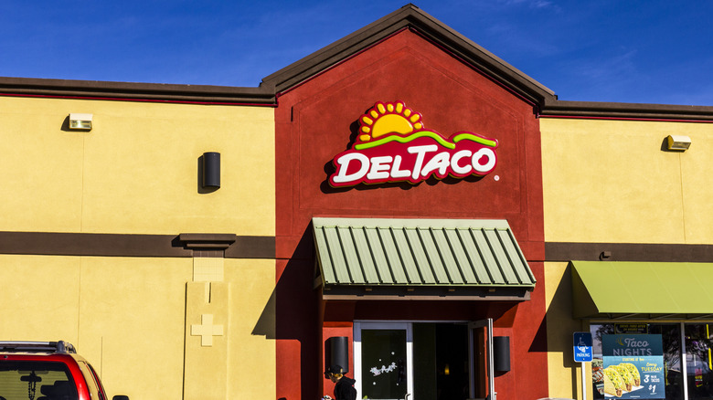 a brightly colored Del Taco restaurant sits against a vibrant blue sky