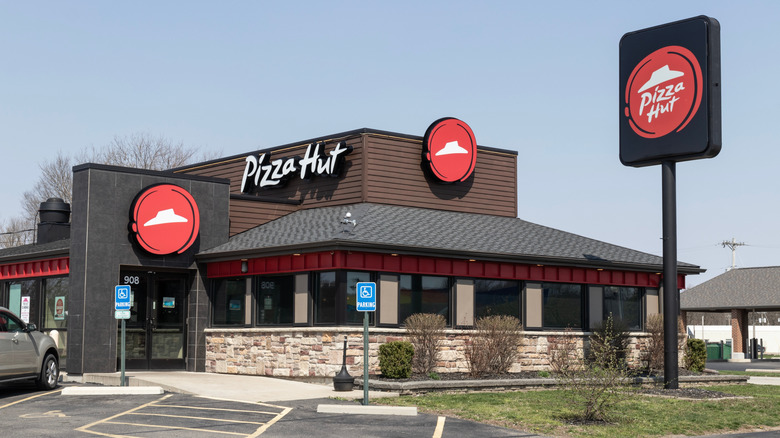 exterior of a Pizza Hut restaurant with a car parked in front