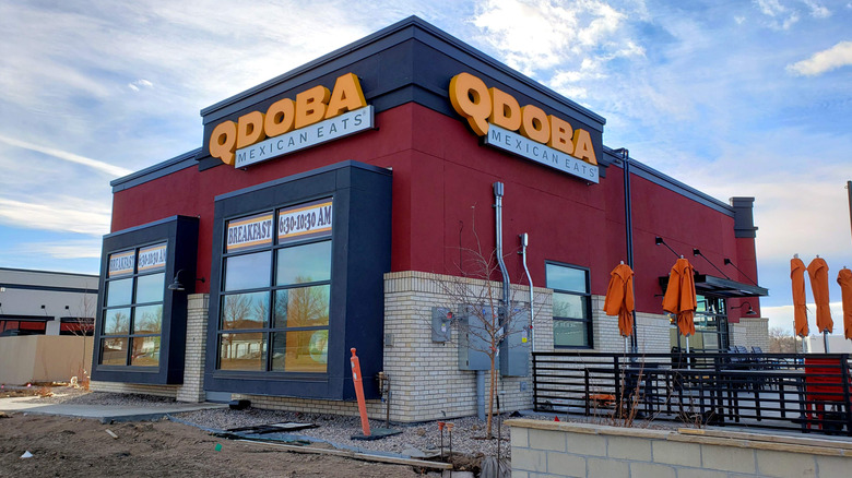 a QDOBA restaurant's storefront against a blue sky