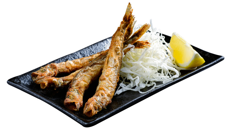 Plate of fried smelt fish with cabbage and slice of lemon