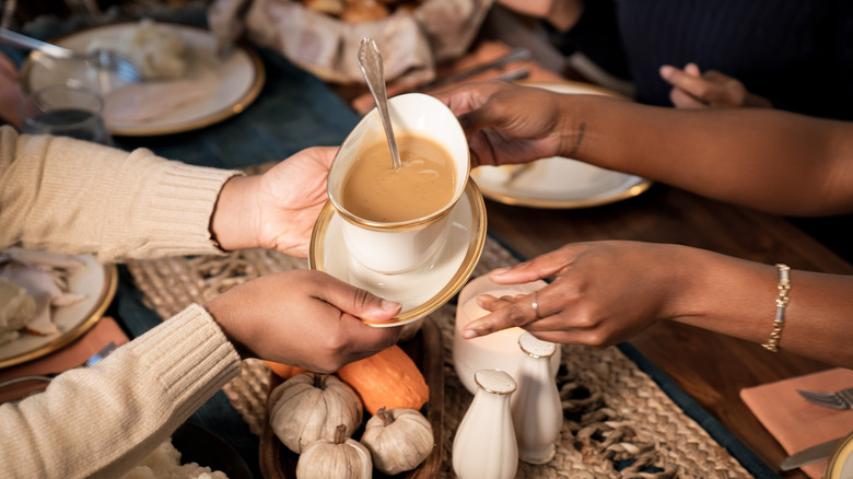 People pass a dish of gravy across a table.