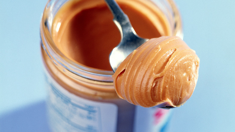 Peanut butter on a spoon balanced on a peanut butter jar