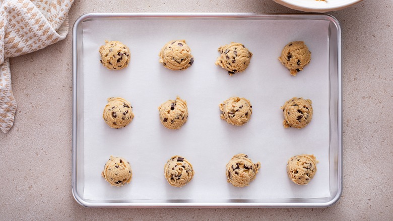 Balls of cookie dough lined up on a baking sheet