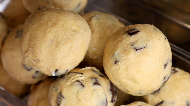 Raw chocolate-chip cookie dough balls stacked up in a container