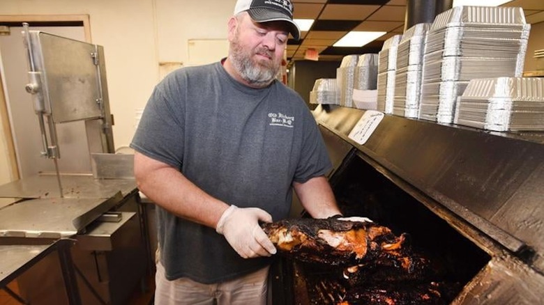 man pulling mutton out of a barbecue pit in kitchen