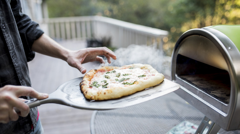 Home cook preparing pizza on a smoker