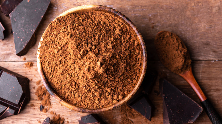 Bowl of cocoa powder with spoon and chocolate bar