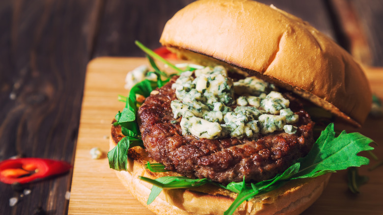 Burger with blue cheese on cutting board