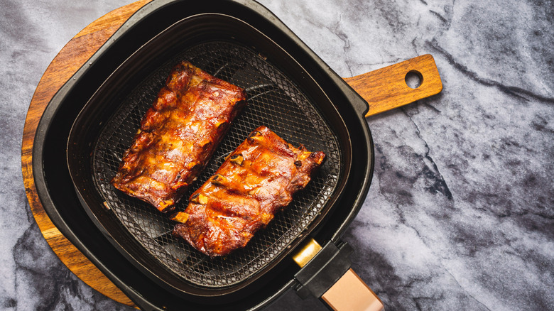 Ribs in air fryer basket against marble backdrop