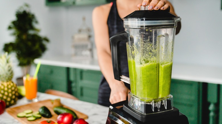 A woman blending up a green smoothie in her blender