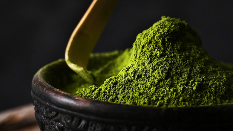 Matcha powder and scoop in brown bowl