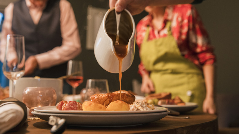 Sauce poured from gravy boat over a plate of food