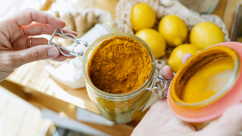 person opening jar of turmeric