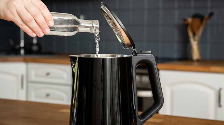 Person pouring vinegar into electric kettle