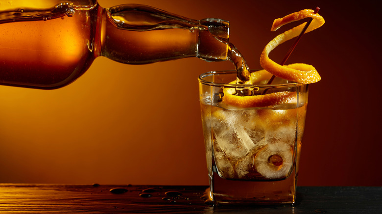 Bourbon poured into a glass with ice and an orange twist