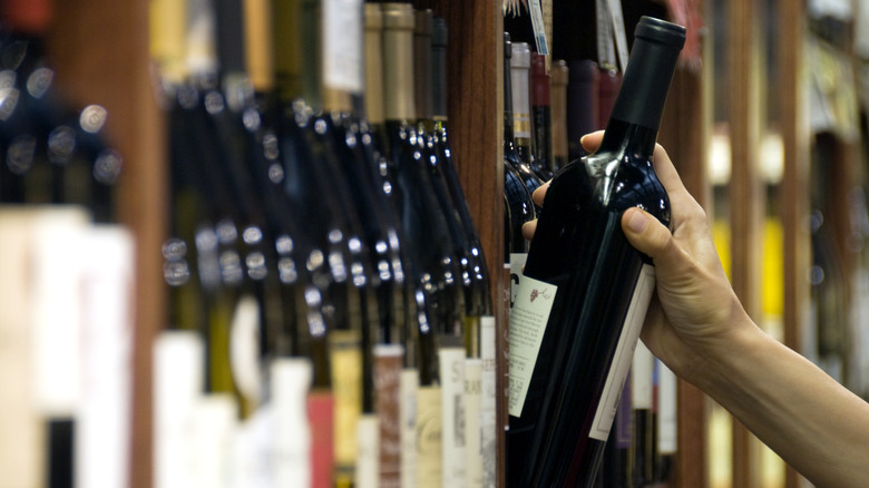 selecting wine bottle from rack