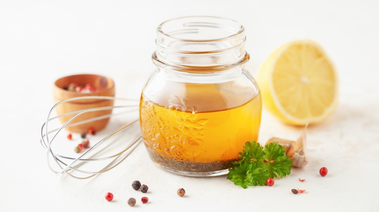 Italian vinaigrette in glass jar next to whisk and lemon