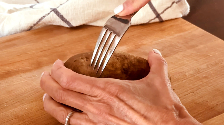 Hand poking potato with fork