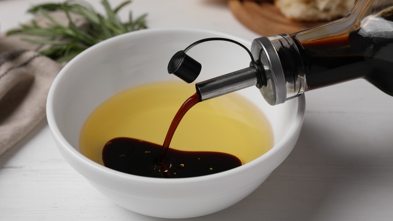 pouring vinegar into a small bowl with oil