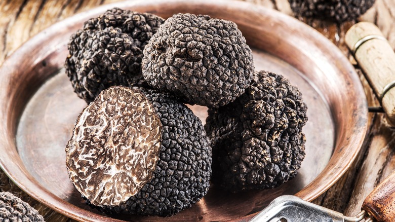 Four black truffles on a brown plate against a rustic background