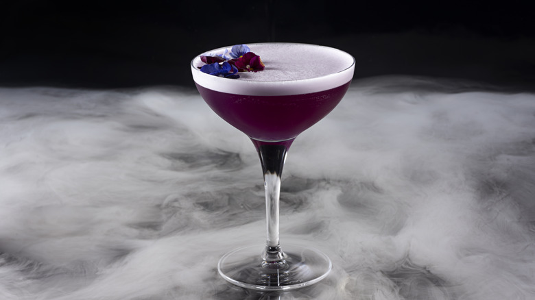 a purple cocktail topped with whipped egg white